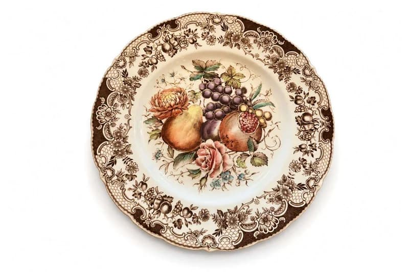 Scalloped ceramic dinner plate with fruit centerpiece and brown floral border